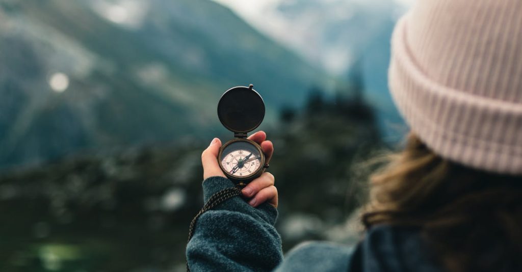 A woman holds a compass in the Canadian mountains, symbolizing adventure and exploration.