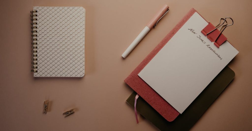 Organized flatlay of notebooks and pen for planning New Year's resolutions.